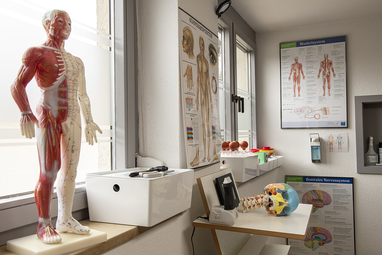 Behandlungszimmer mit medizinischen Plakaten an der Wand